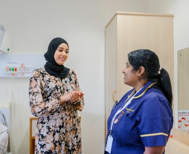 A consultant and a nurse convers in a patient's room
