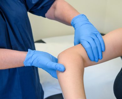 A nurse examines a patient's elbow