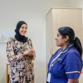 A consultant and a nurse convers in a patient's room