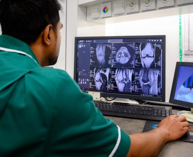 An MRI technician looks at scans on their computer