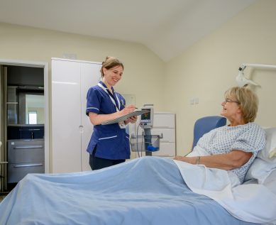Nurse speaks with a patient in their private room