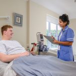 A nurse talks with a patient in their private room