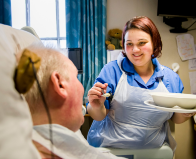 Nurse helping patient to eat at mealtime