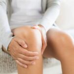 Young woman feeling knee due to pain